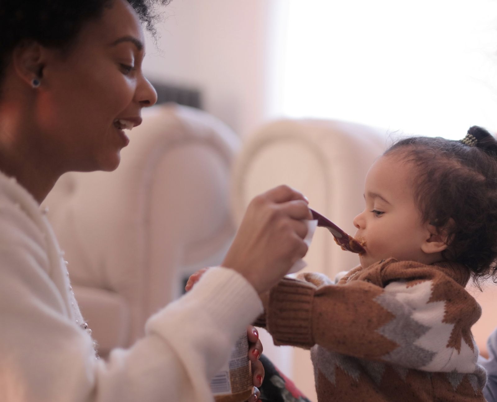 Een ouder geeft een peuter met de lepel te eten, een traditionele aanpak voor de start met vast voedsel