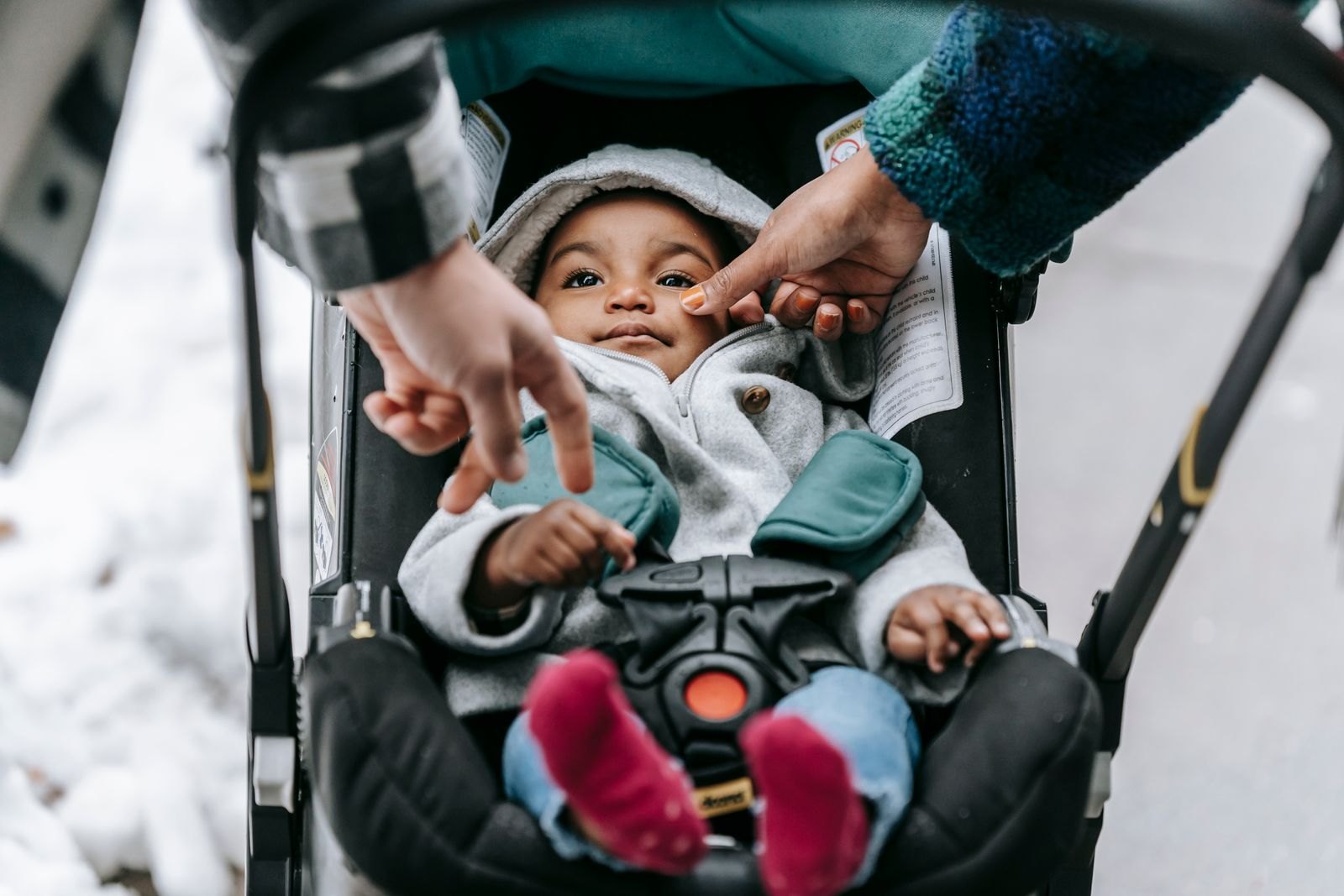 Ouders passen de zitting en het tuigje van een baby in een autostoeltje aan, buiten bij de auto