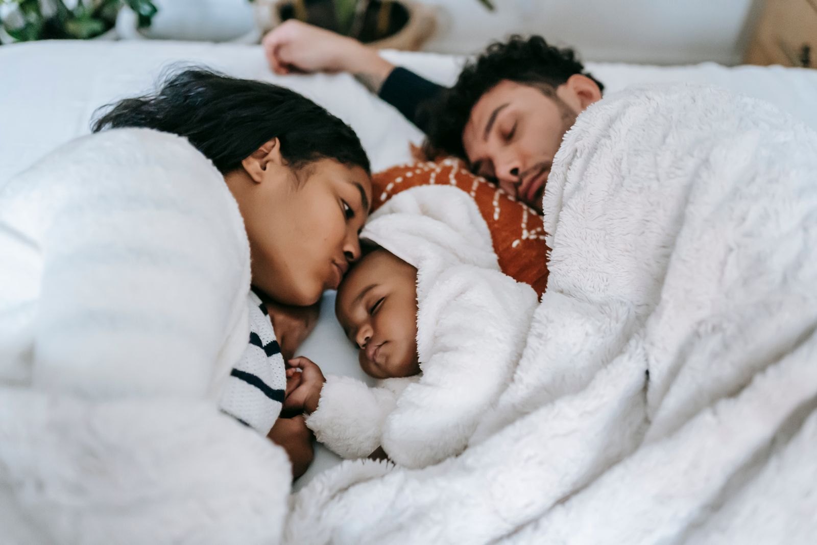 Ouders liggen dicht tegen elkaar met hun baby in bed