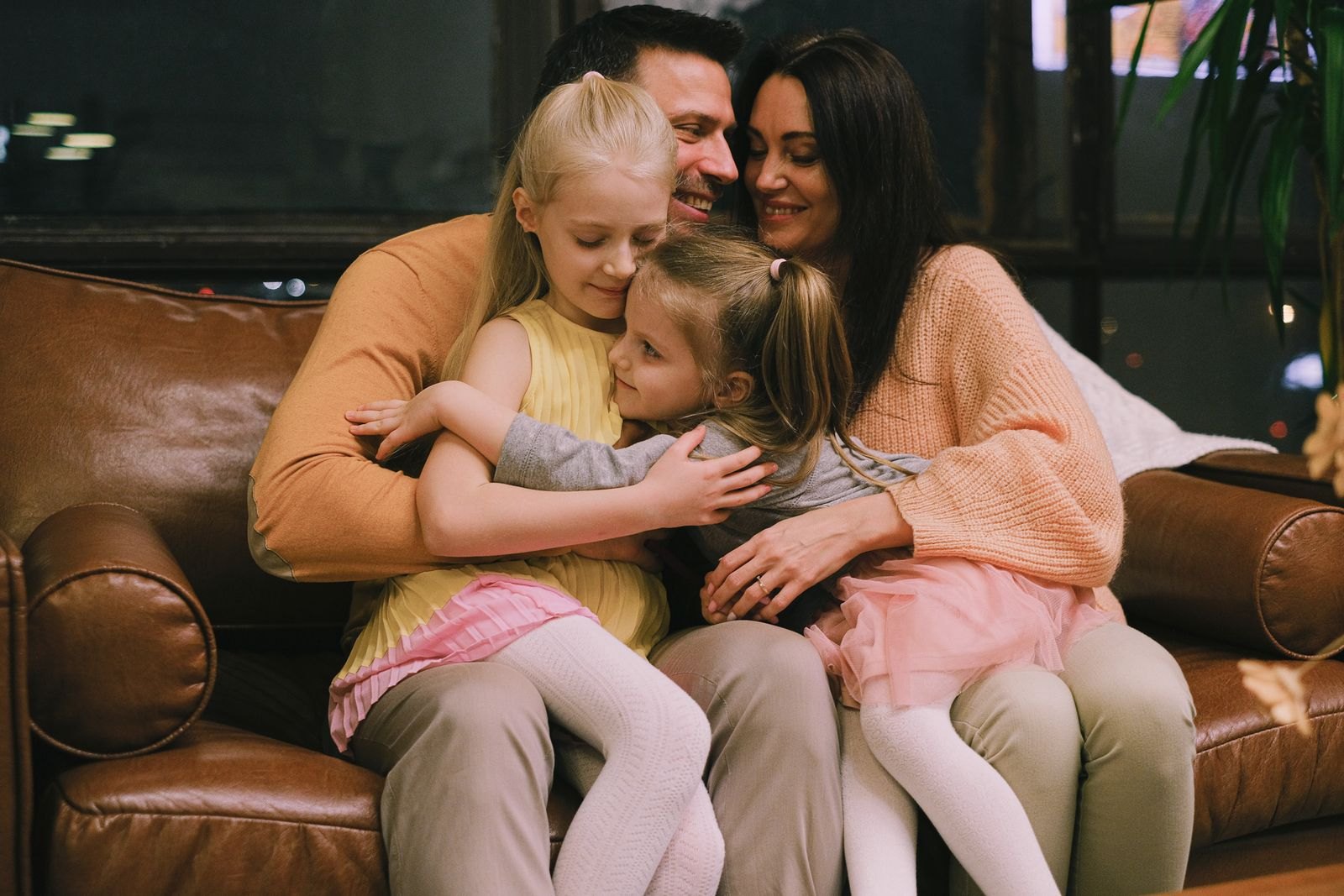 Ouders knuffelen hun kinderen op de bank, een moment van warmte en verzoening in huis