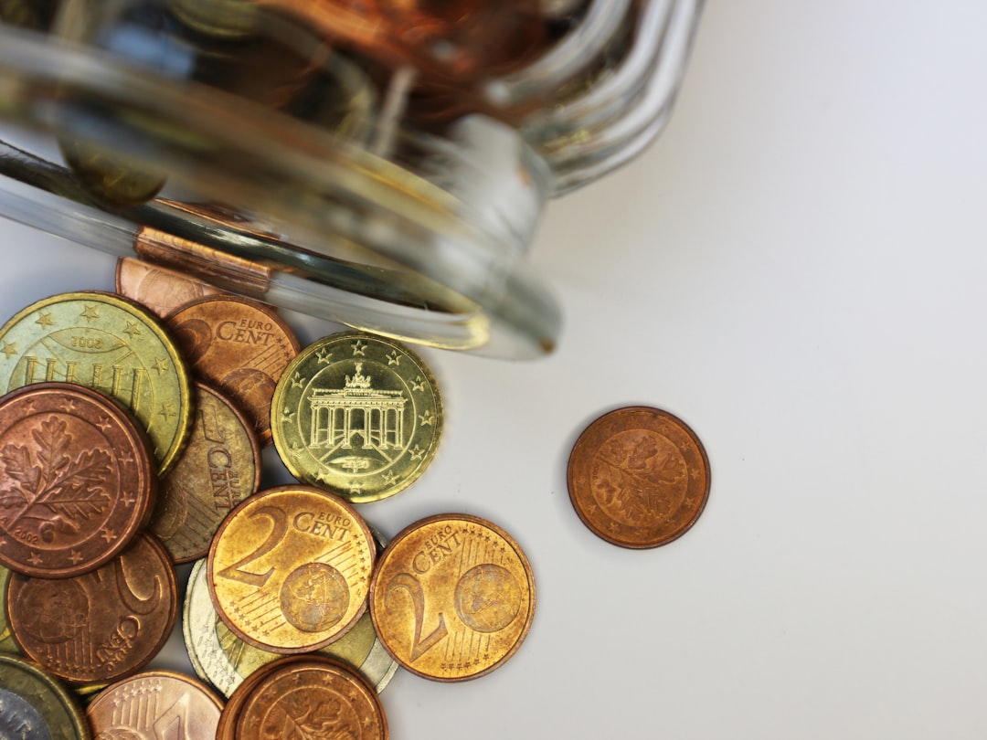 Euro-Centmünzen mit dem Brandenburger Tor, die aus einem umgekippten Glas rollen