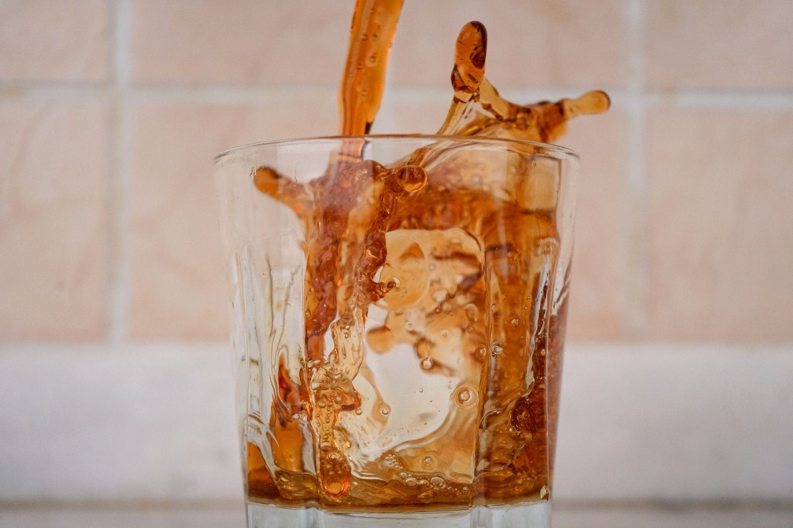 Cola being poured over ice into a tall glass, a common everyday source of the added sugar that drives glycation