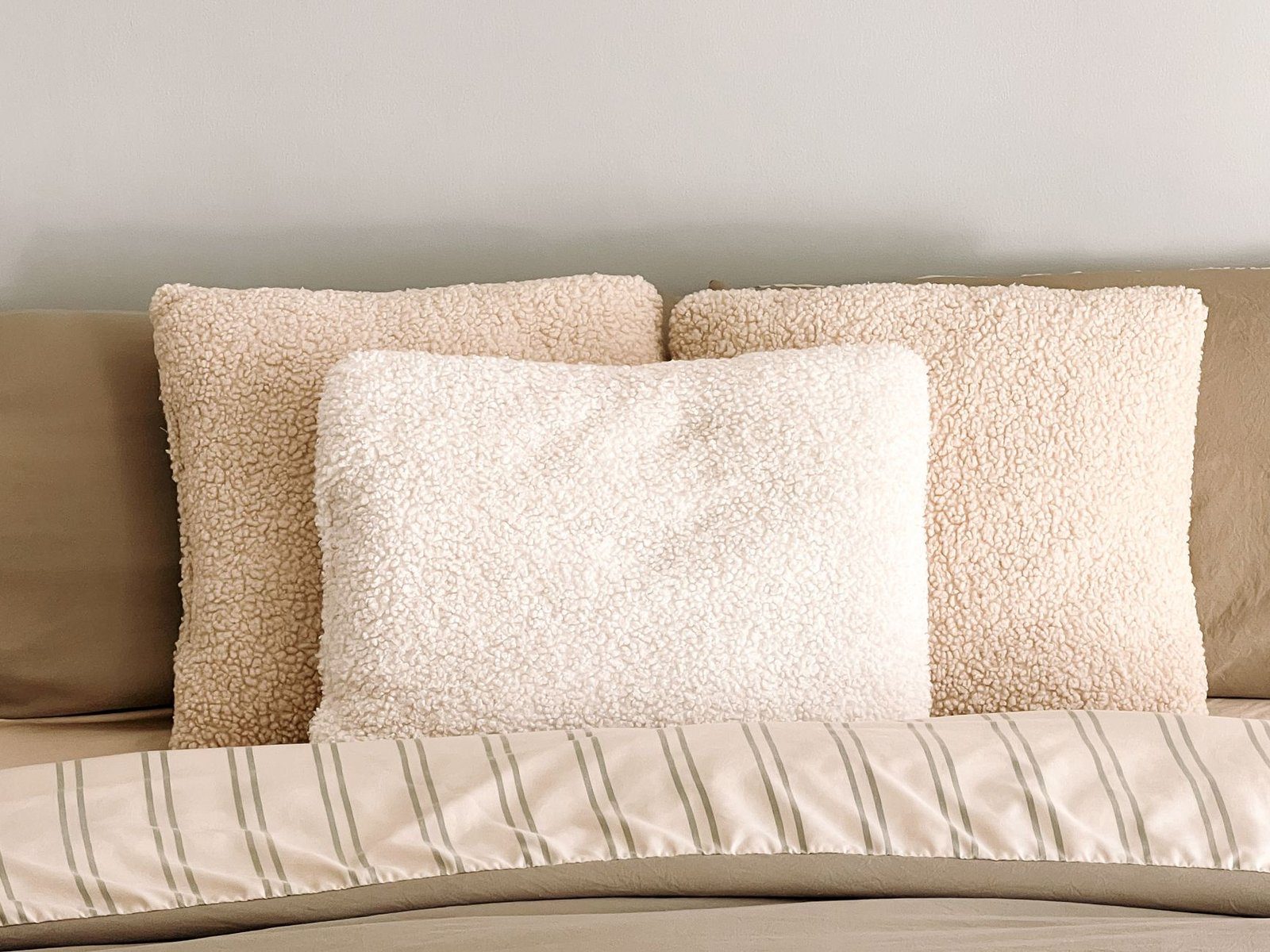 A pillow on a made bed, representing the seven-hour sleep window that gets trimmed on busy weeks