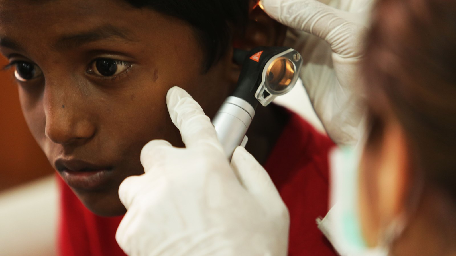 Un médecin examine l'oreille d'un enfant avec un otoscope, le seul moyen de confirmer réellement une otite