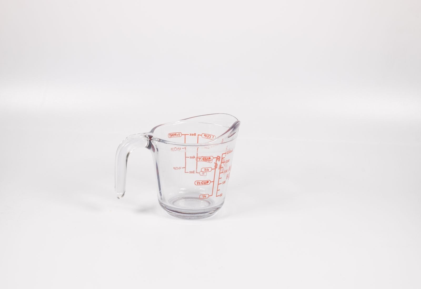 Un verre doseur gradué posé sur un fond clair