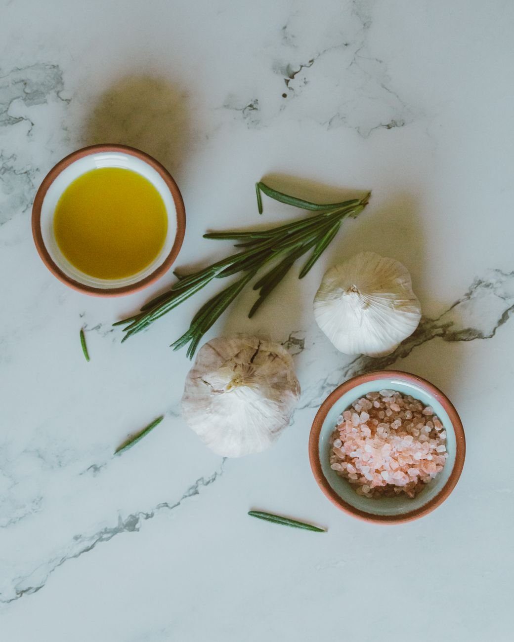 Aglio ed erbe aromatiche fresche su un piano di marmo, ingredienti tipici della dieta mediterranea