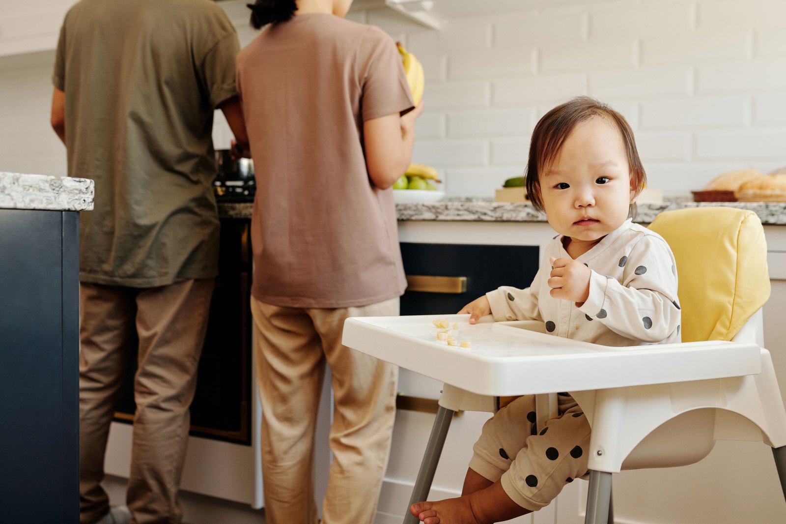キッチンで両親が家事をする傍ら、ハイチェアで自食する赤ちゃん