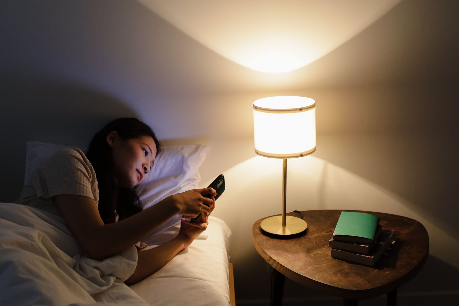 夜、ランプの明かりの下でベッドに横になる女性