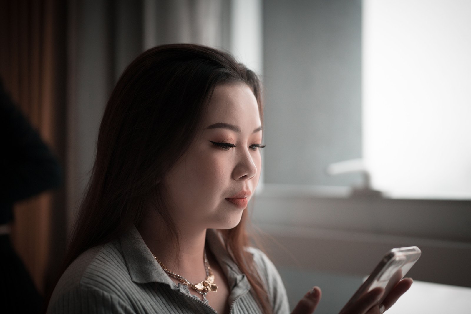 スマートフォンの画面を見ながら考え込む女性