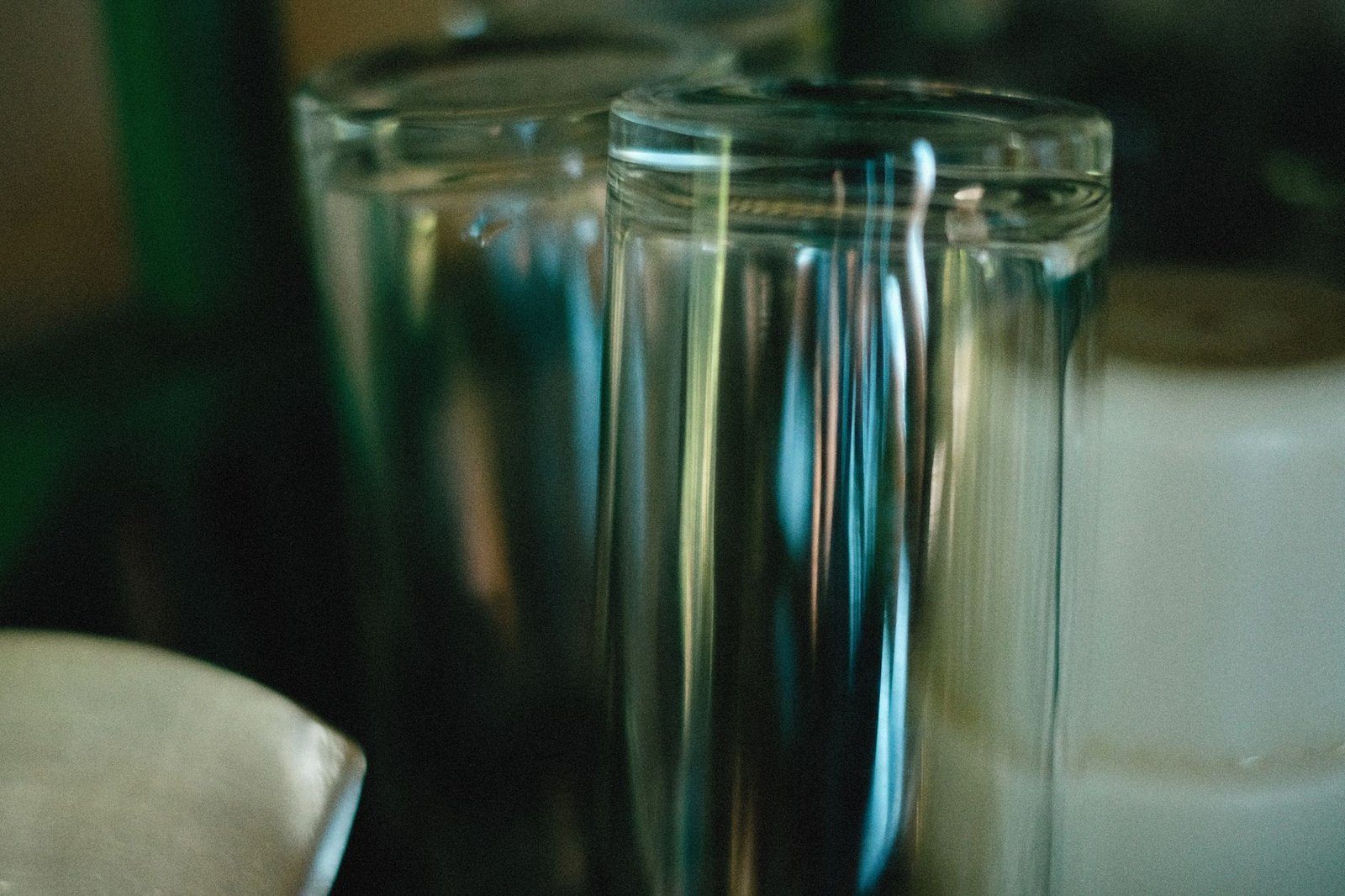 空のガラスコップ二つを至近距離で撮影した、背景が暗くぼけた写真